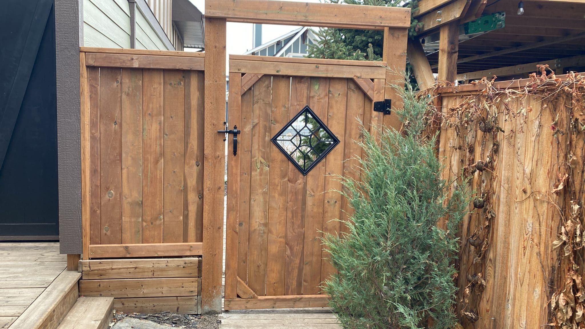 Custom cedar gate with a diamond-shaped decorative glass insert.