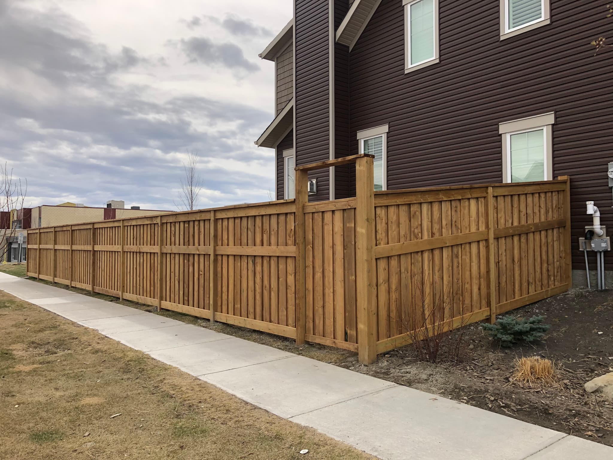 Fortress-style cedar privacy fence with staggered pickets on a corner lot.