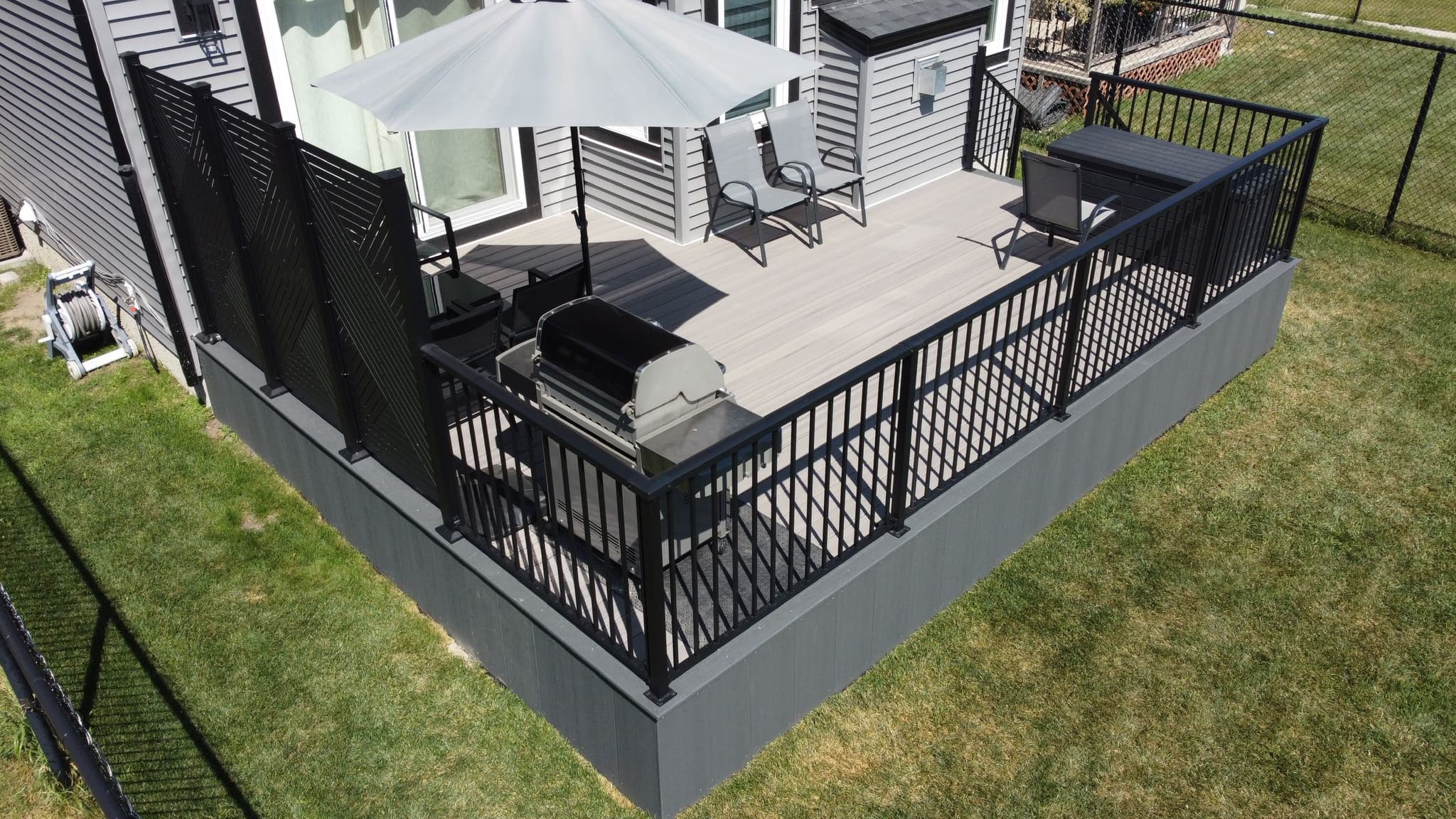 Modern composite deck in Calgary backyard with black aluminum railing and privacy screen