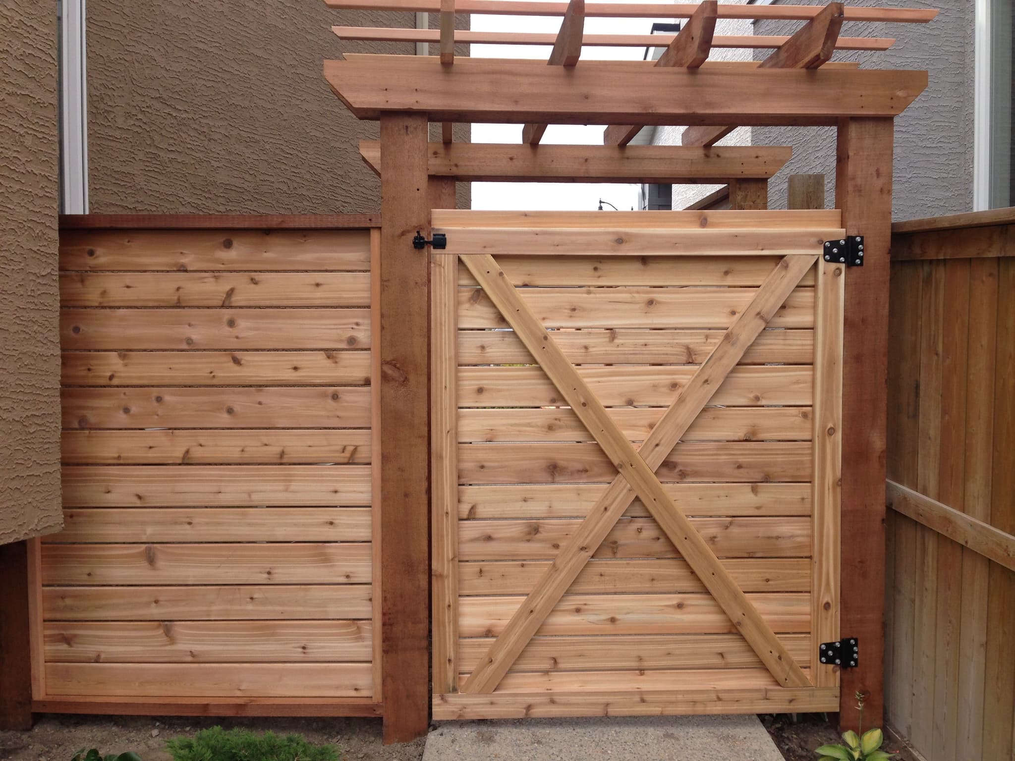Cedar wood fence with horizontal slats and custom gate, built for durability in Calgary weather conditions.