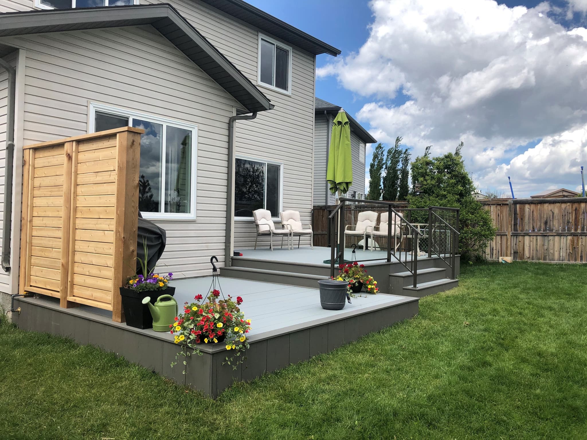 Modern Calgary backyard deck with glass railing, privacy wall, and composite decking