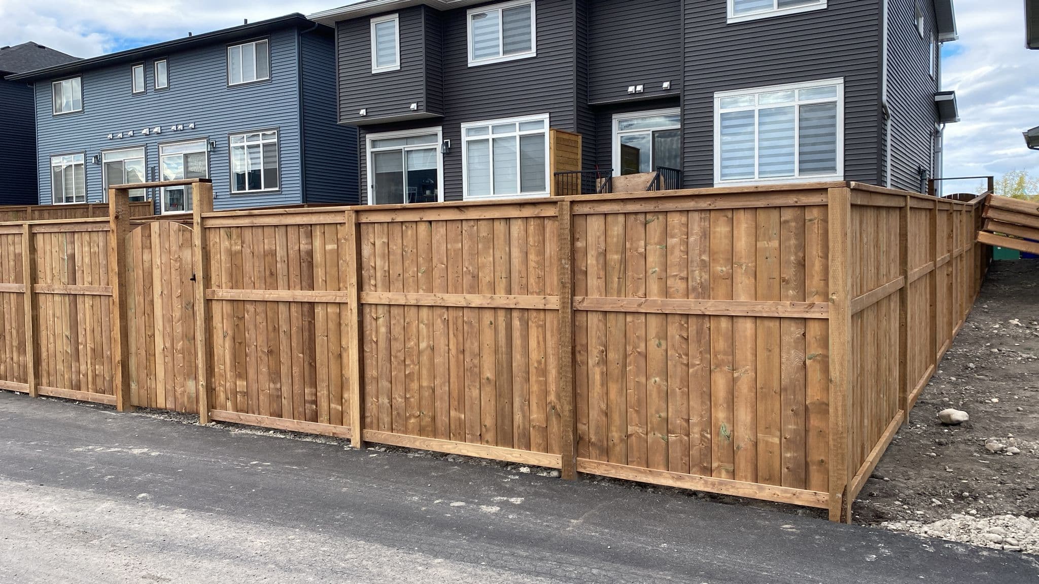 Wood fence installation in Calgary with vertical boards and gate, built for durability in changing weather conditions