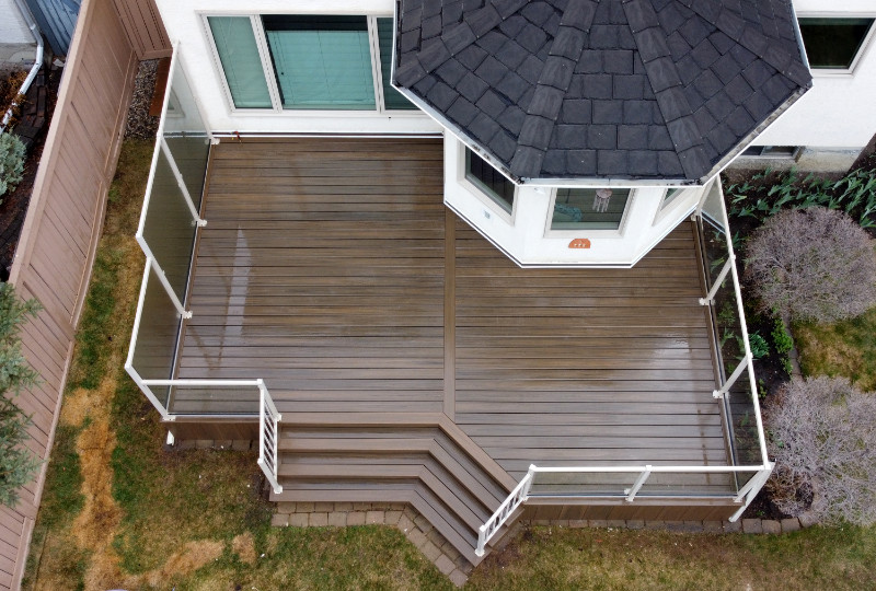 Trex Toasted Sand deck, with full Trex fascia skirting, clear glass railing, and glass privacy wall.