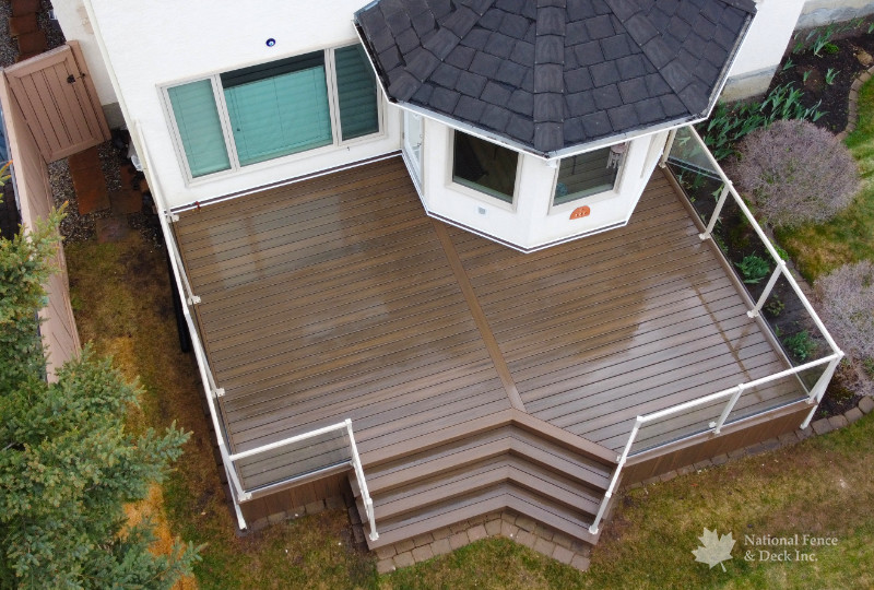 Trex Toasted Sand deck, with full Trex fascia skirting, clear glass railing, and glass privacy wall.