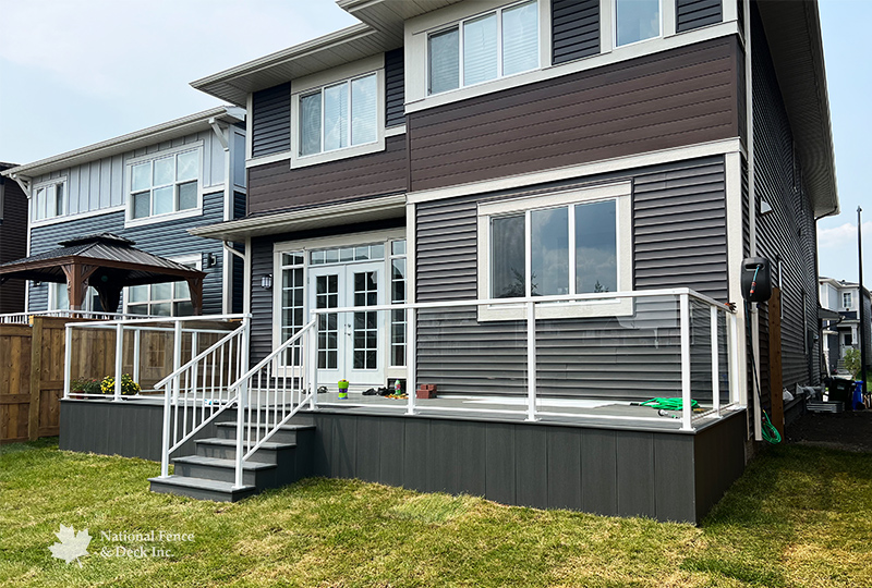 Trex Clam Shell deck with white aluminum railings and clear glass inserts.